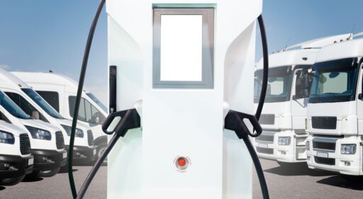 Electric vehicles charging station on a background of trucks and vans. Electric Vehicle Fleet Management concept.
