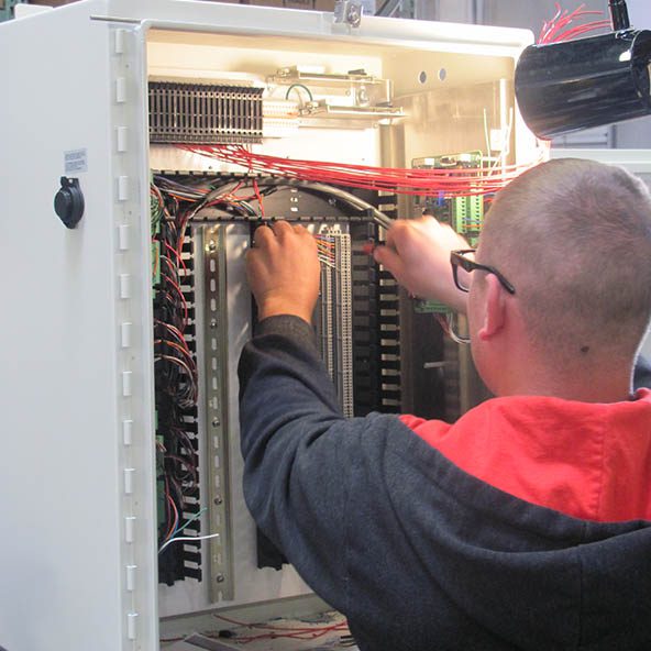 Technician providing industrial electric services on a control panel.